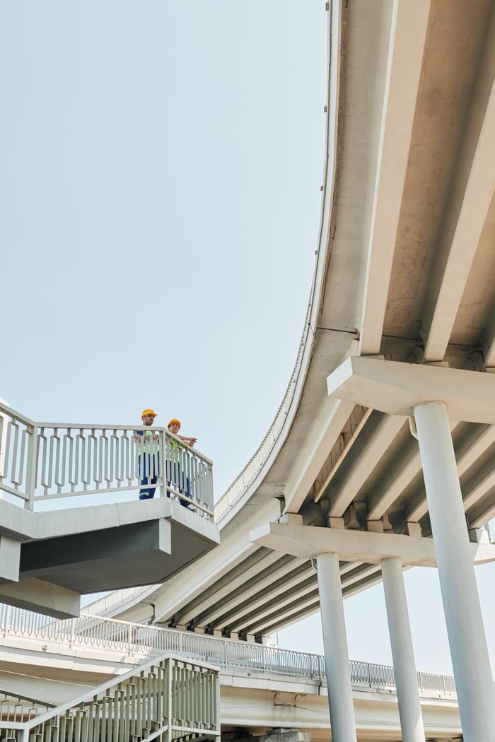 Two engineers observing a modern overpass, showcasing urban construction and engineering feats.
